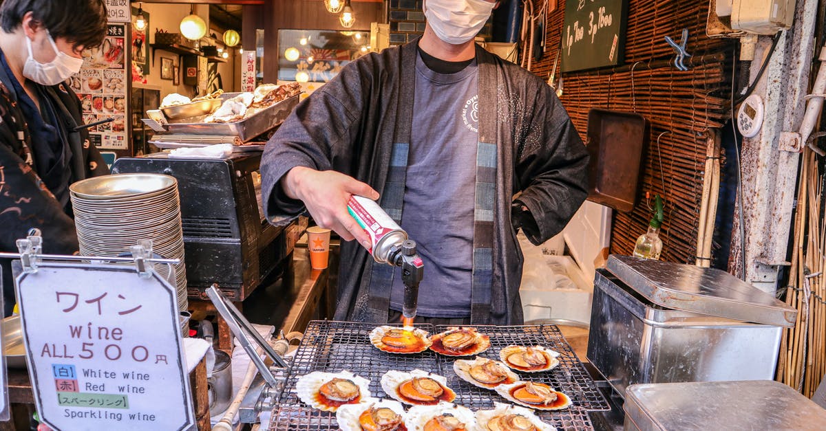 I cannot understand how to properly fry seafood - Asian man in mask frying clams on street market