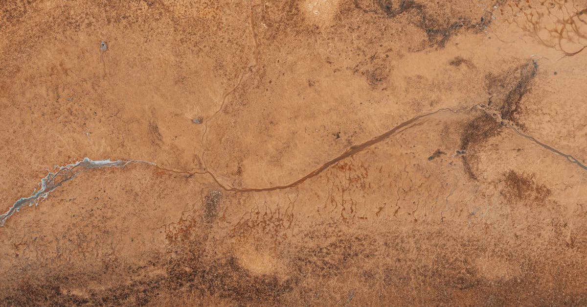 I have a frozen brown bear (roast?) from somewhere in Alaska - Drone view of textured background representing frozen creek on rough brown land with spots in daytime