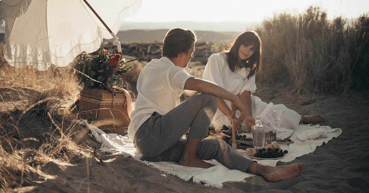 I love food and the public but my body can't handle it anymore [closed] - Young loving couple having romantic picnic sitting on white blanket with food and drinks under white umbrella