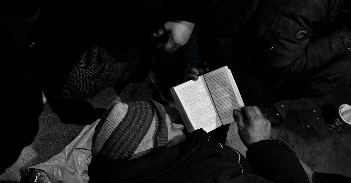 I need to keep blacks beans and rice warm. - Black and white of homeless man lying on floor and reading book in night shelter for homeless