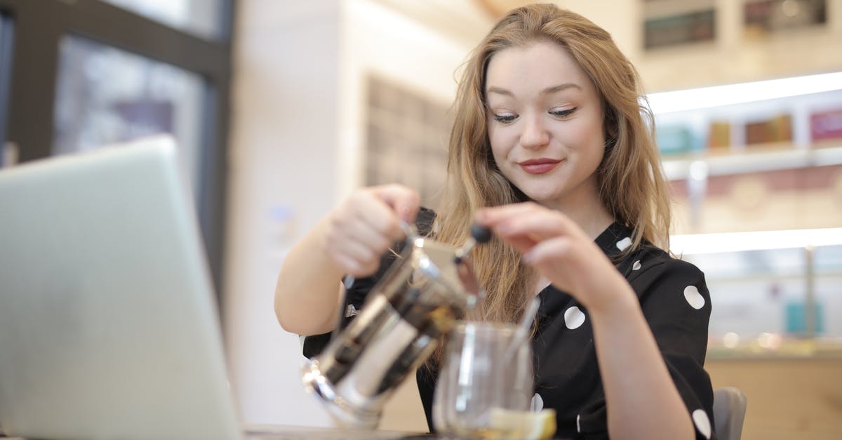 Ideal coffee grind for a French Press? - Relaxed female in trendy polka dot dress pouring hot beverage from french press into glass mug while chilling in cafe during weekend