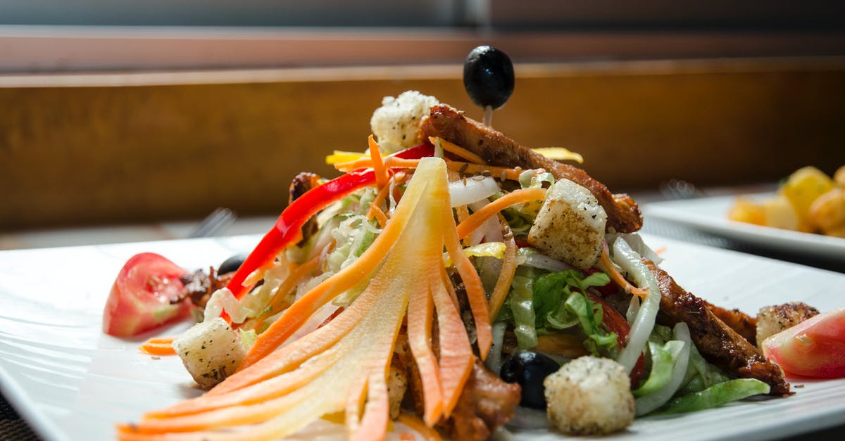 Ideal way to cook a chicken - Appetizing healthy salad with fresh vegetables and fried chicken decorated with black olives and served in white plate