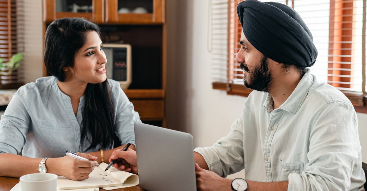 Ideas for using garlic scapes (other than in pesto)? - Indian male in turban and wristwatch typing on netbook while interacting with happy female coworker with notebook and pen sitting at table in office and looking at each other