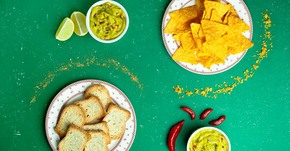 Identifying a white crispy garnish to a pork dish - Flat lay of nachos near guacamole sauces and sliced white bread on plates