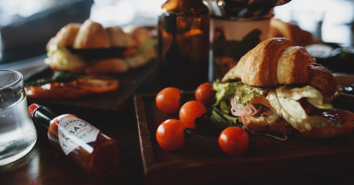 Identifying a white crispy garnish to a pork dish - Crispy fresh croissant sandwich served with tomatoes in contemporary restaurant