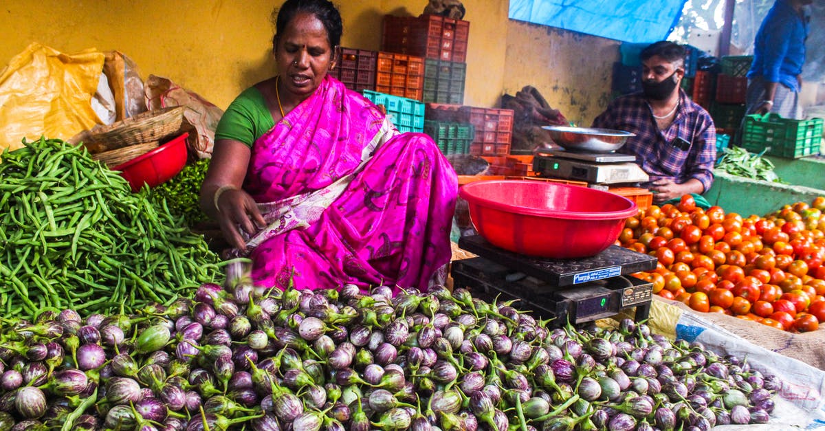 Identifying quality fruits/vegetables at a farmers market - Woman Sitting Near the Vegetables