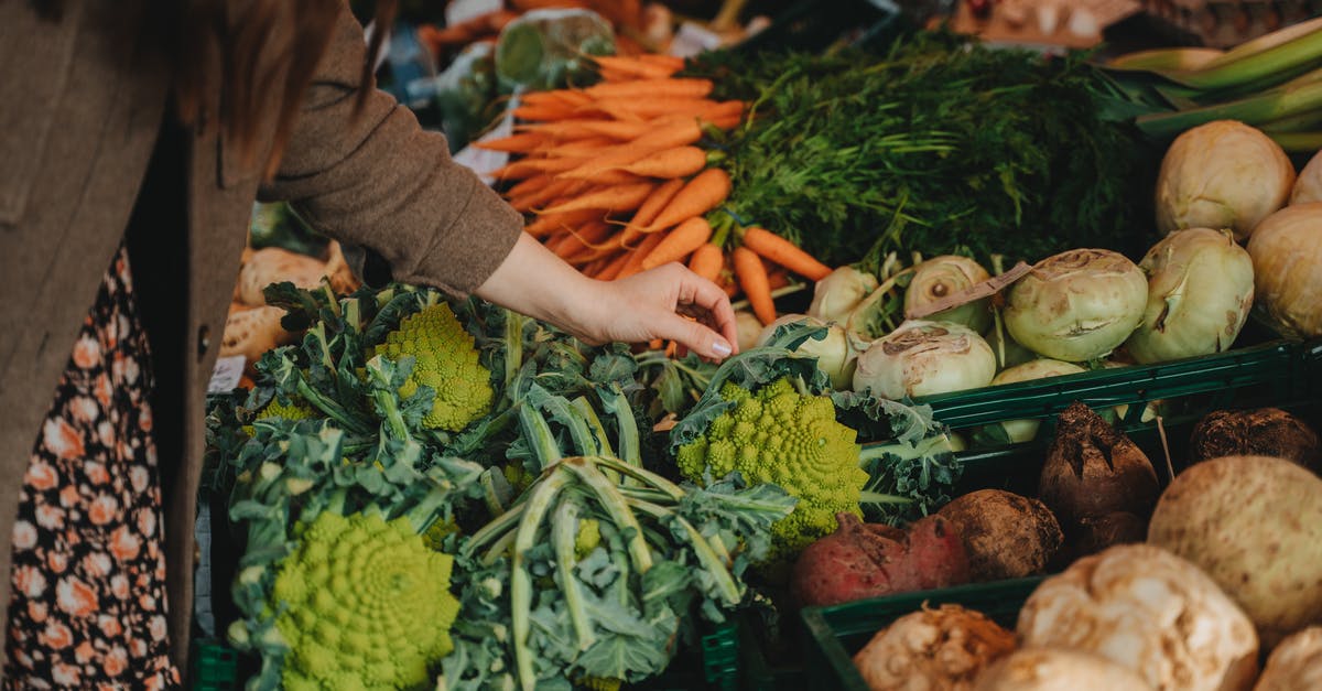 Identifying quality fruits/vegetables at a farmers market - Photograph of a Person's Hand Picking Vegetables