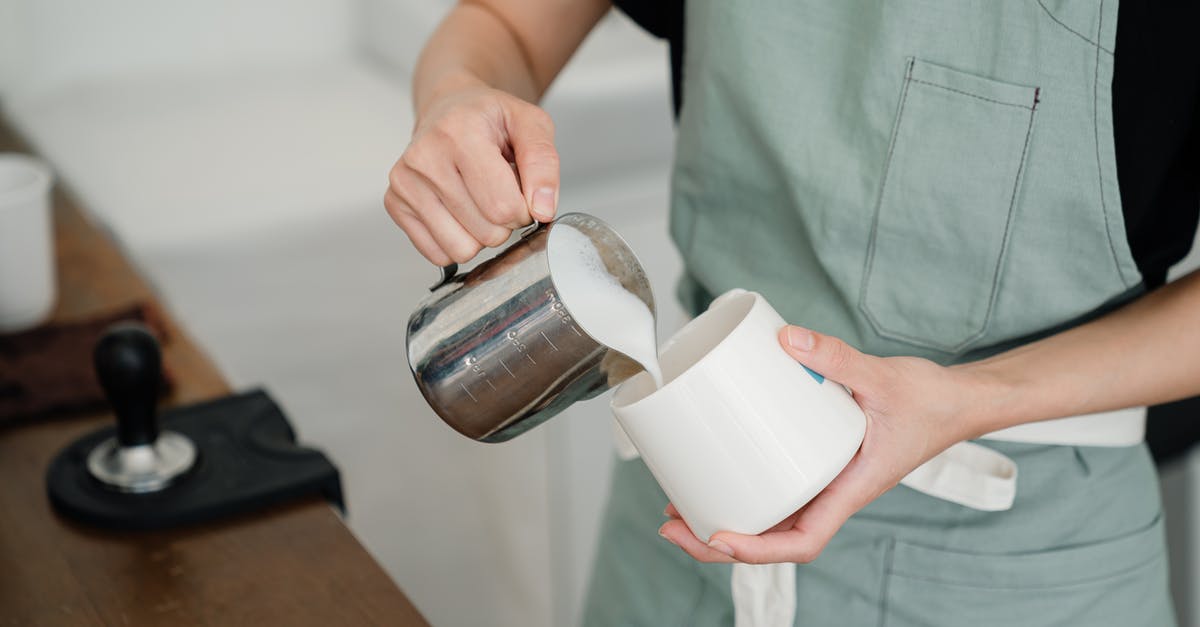 If I'm using milk as an ingredient in soup, how can I prevent it from curdling? - From above of crop young anonymous person in apron pouring milk into white mug while preparing aromatic latte