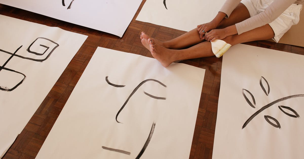 image on rice paper - From above of faceless barefoot casually dressed woman with brush sitting on floor while placed artworks in abstract style