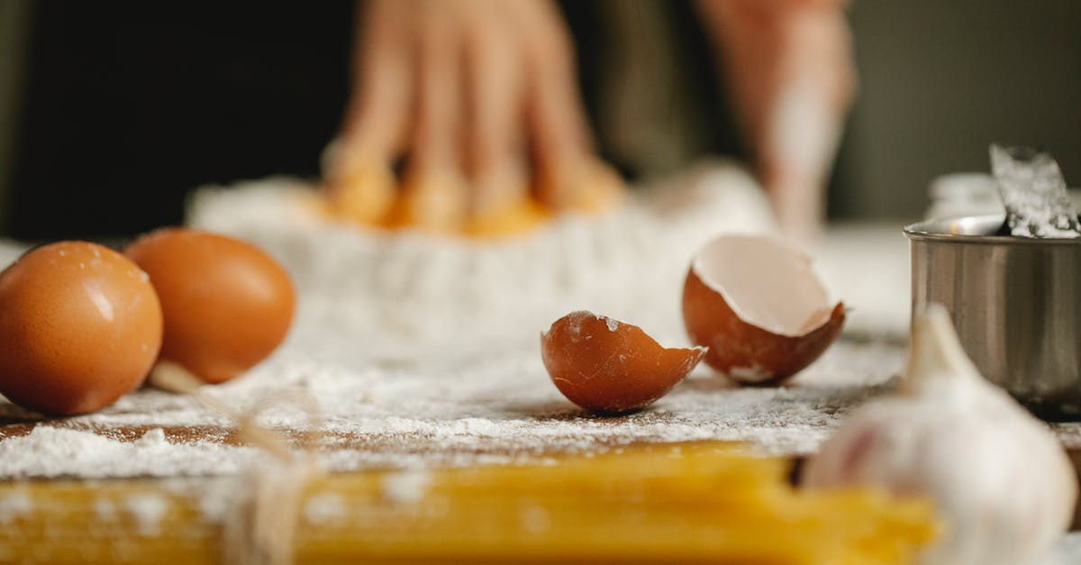 Impact of using egg yolks vs whites in a spaghetti dish? - Table for cooking in kitchen with eggs eggshells spaghetti and garlic on blurred background