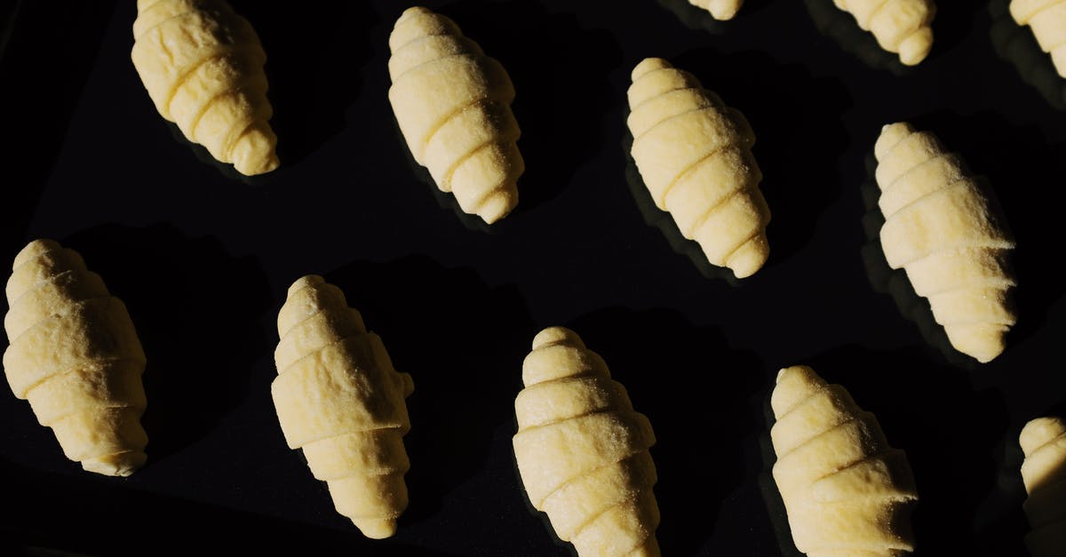 Impossible to Roll Croissant Dough - Top view composition of uncooked raw croissant dough arranged on surface of black glass in dark light