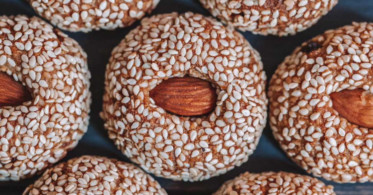 In what proportion should the given ingredients be combined to form a cookie? - Top view of background representing tasty biscuits with whole almonds in center and sesame seeds on top