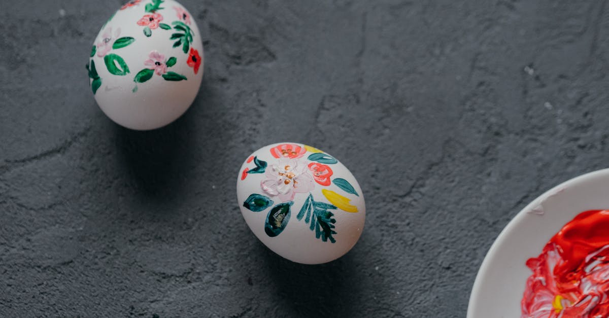 Incorporating capsicum oil into a chicken breading - Top view of white chicken eggs decorated with painted colorful floral ornament laced in rough gray table during Easter preparation