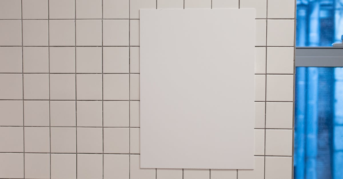 Info about spelt - Blank white placard hanging on wall covered with white tiles inside of building