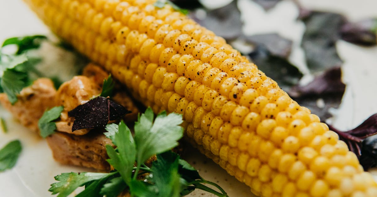 Ingredient Identification: Hong Kong restaurant spicy spice - Tasty boiled corn cob served on table with herbs