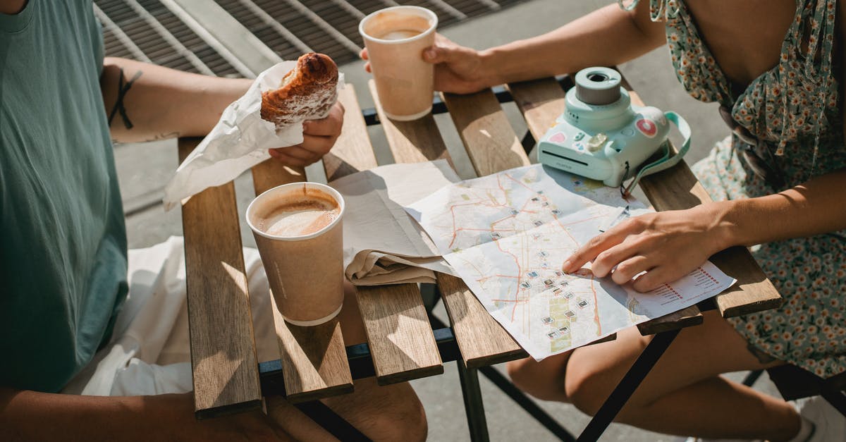 Instant coffee with only milk? - From above of crop anonymous couple searching route in map while having coffee and croissant