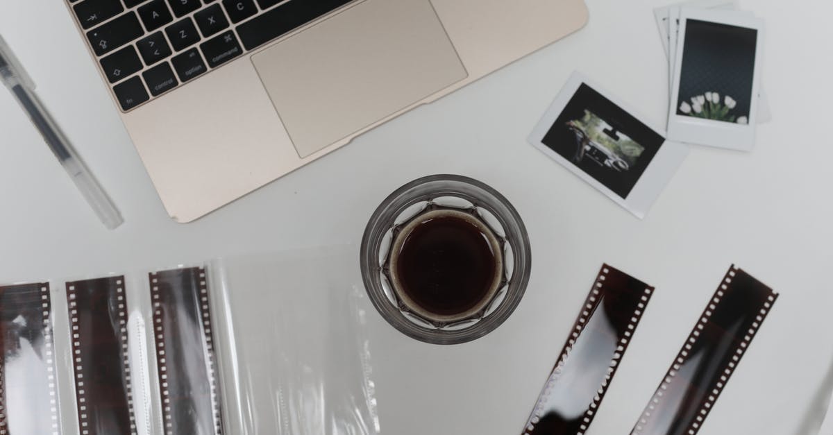 Instant coffee with only milk? - Top view of coffee cup with vintage instant photos and negative film strips placed on table with opened laptop