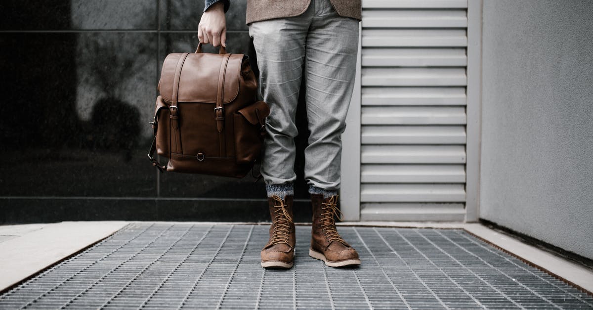 Is beef 'aged' in vacuum packed bags? - Photo of Man in Brown Blazer,Gray Pants, and Brown Boots Holding Brown Leather Bag Standing Outside Building