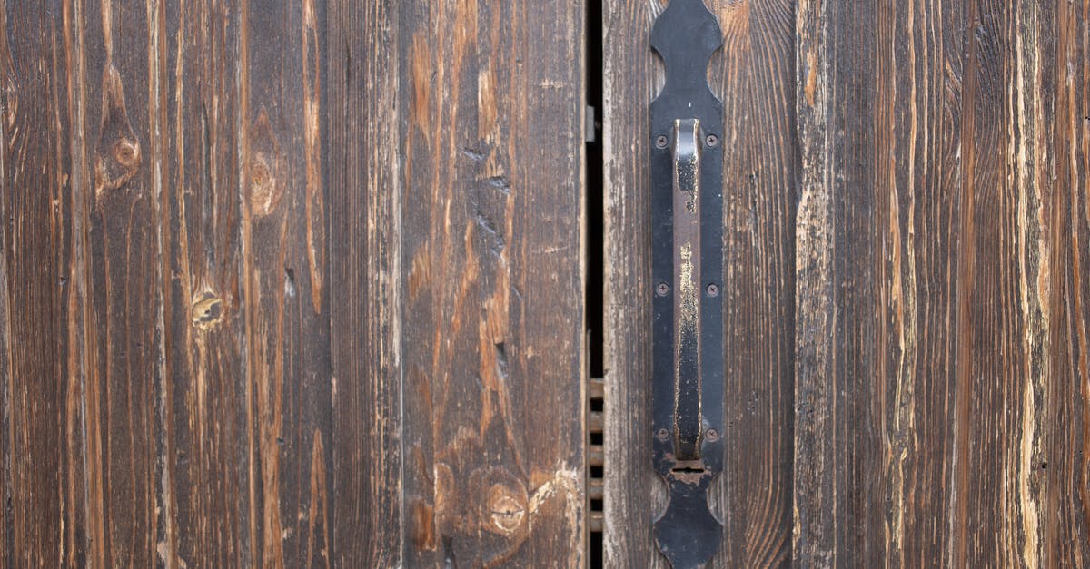 Is burnt microwave safe to use? - Closeup of weathered old rusty brown locked wooden door with cracks on surface with aged metal handle