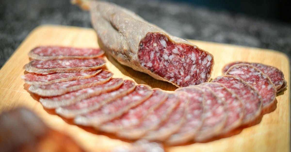 Is cured meat broth edible? - Cold cuts of delicious smoked sausage placed on wooden board amidst sausage slices in kitchen