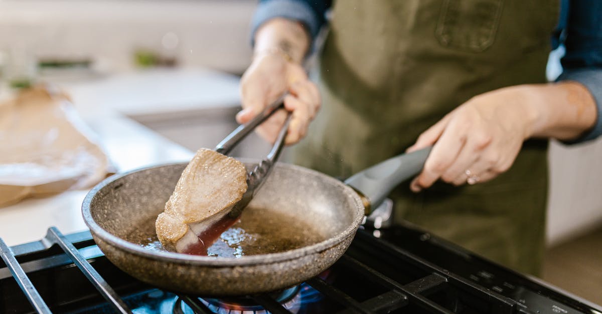 Is exposed copper pan safe for frying fish? - Chunk of Tuna Fish Meat Turned on Frying Pan by Kitchen Pincers in Chefs Hand