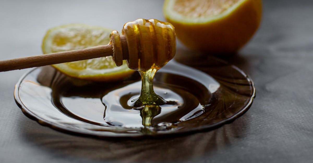 Is honey considered vegan? - Honey dipper above saucer with lemon