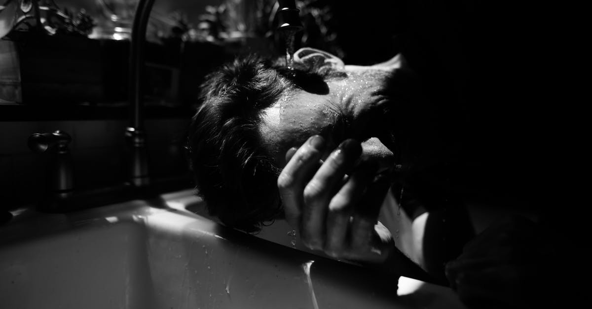 Is hot tap water safe for cooking? - Black and white of unrecognizable male standing near double sink under water flowing from tap in sunny day