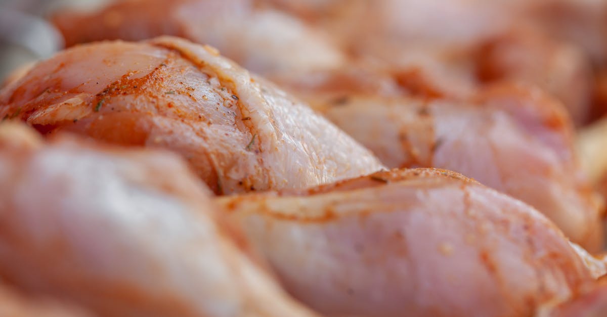 Is it contaminating the spice to touch it after touching raw meat? - Closeup of tasty raw chicken legs with seasoning placed in row in daylight