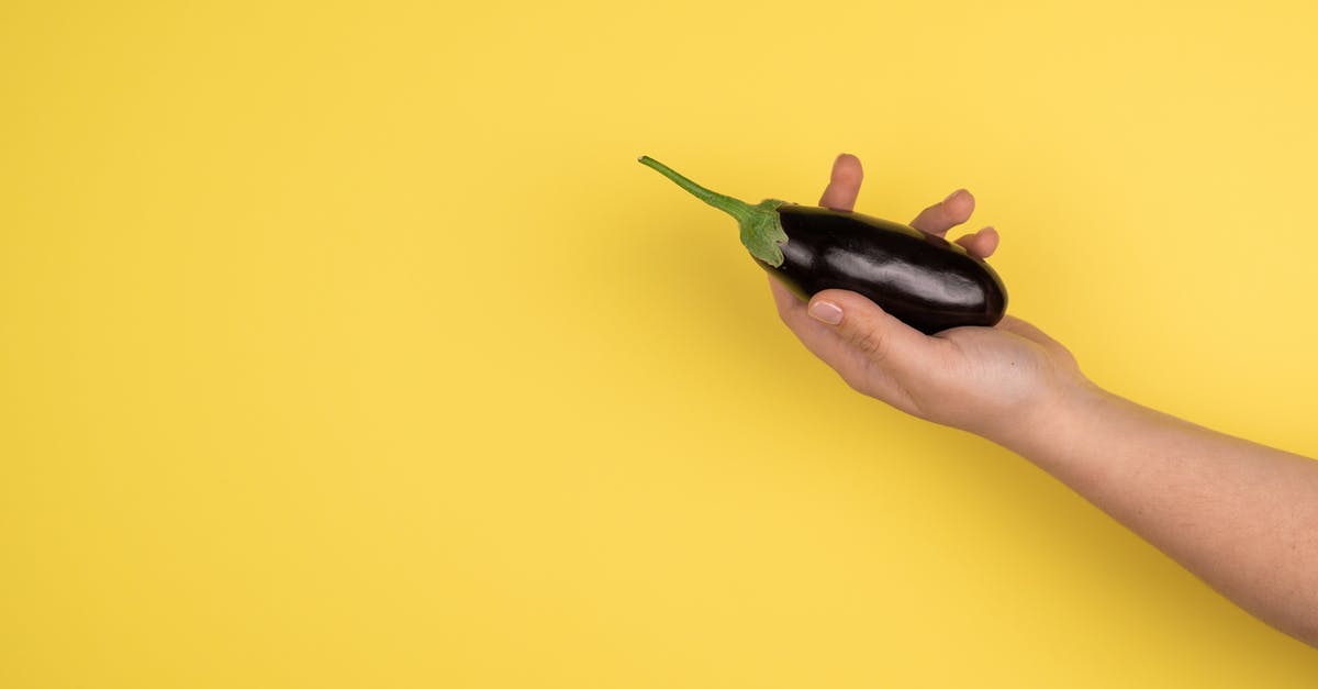 Is it necessary to peel aubergine? - Hand of crop person with eggplant