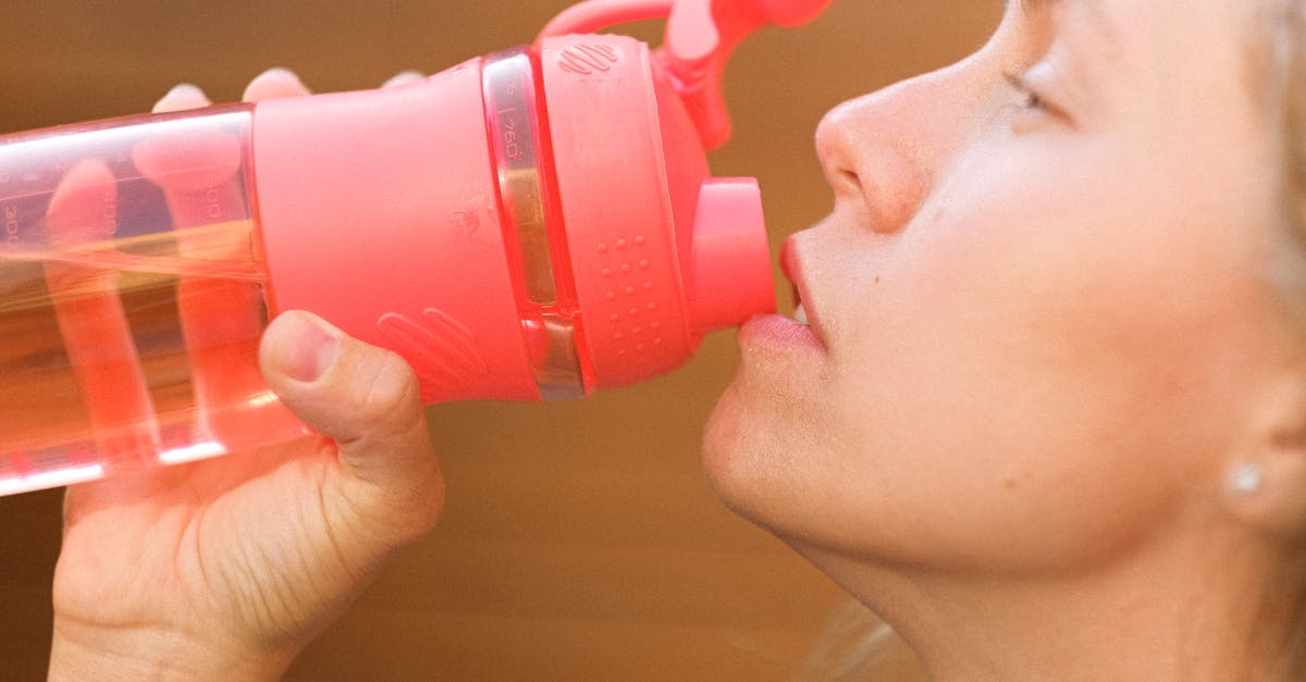 Is it ok to keep reusing a water bottle indefinitely? - Side view crop pretty thirsty female drinking fresh cold water from reusable bottle outside cottage