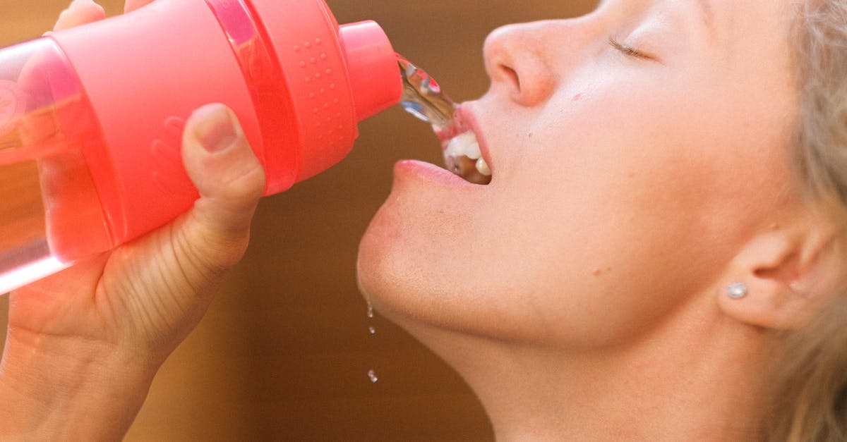 Is it ok to keep reusing a water bottle indefinitely? - Crop tired young female pouring refreshing clean water into mouth from reusable bottle after intense training