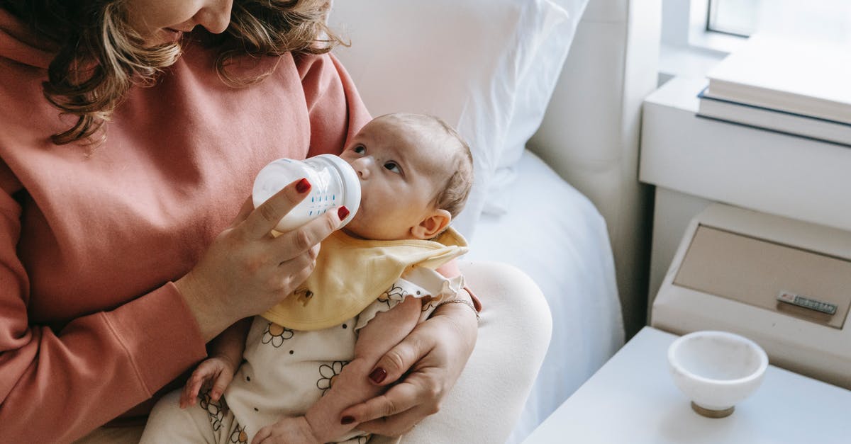 Is it okay to feed milk powder to sourdough starter? - From above of crop happy young mother in casual clothes smiling while hugging and feeding adorable newborn from bottle sitting on comfortable bed