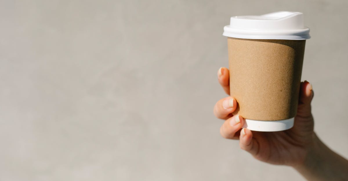 Is it possible to brew good tea on a mountain? - Anonymous woman demonstrating paper cup of takeaway coffee against gray background in sunny morning