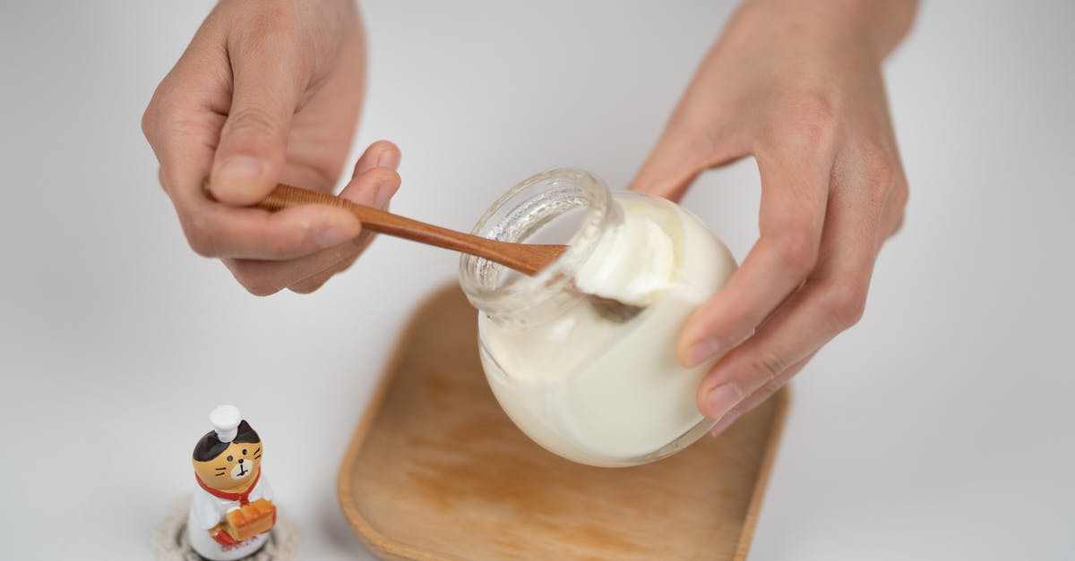 Is it possible to make yogurt and cheese from spoiled milk? - Crop man taking natural yogurt with spoon from jar