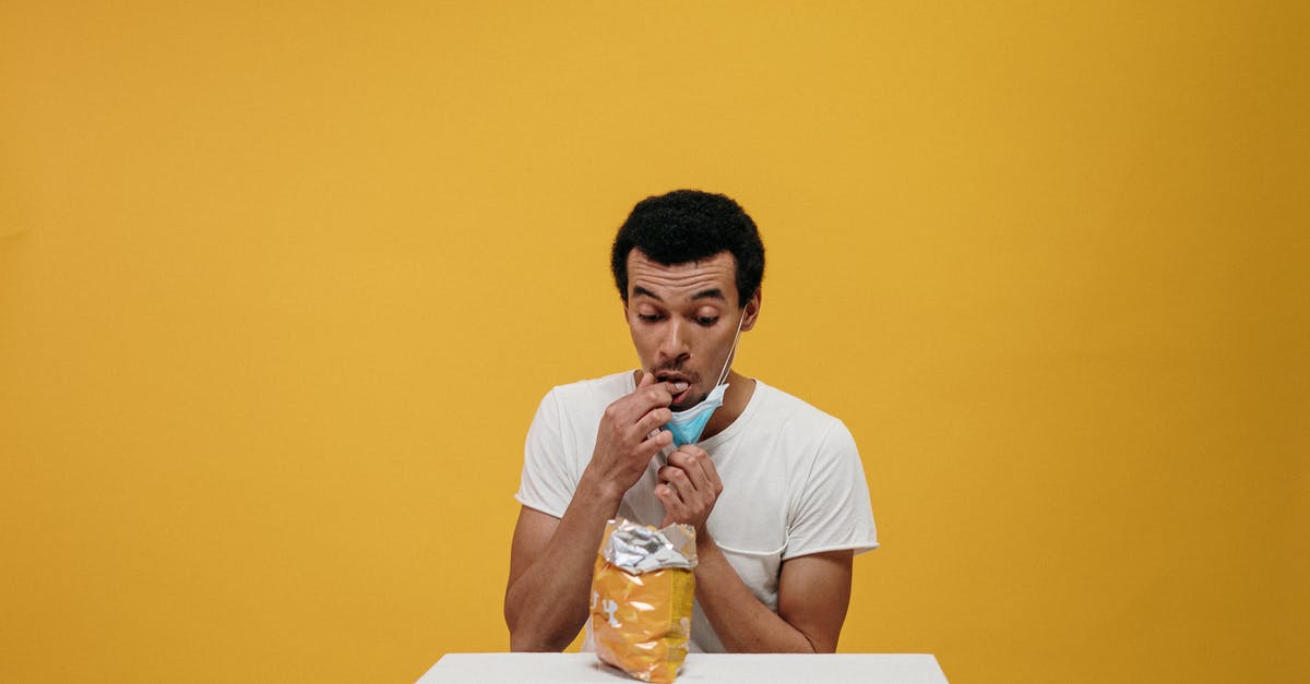 Is it safe to eat off of partially tarnished silver? - Man in White Crew Neck T-shirt Eating Chips