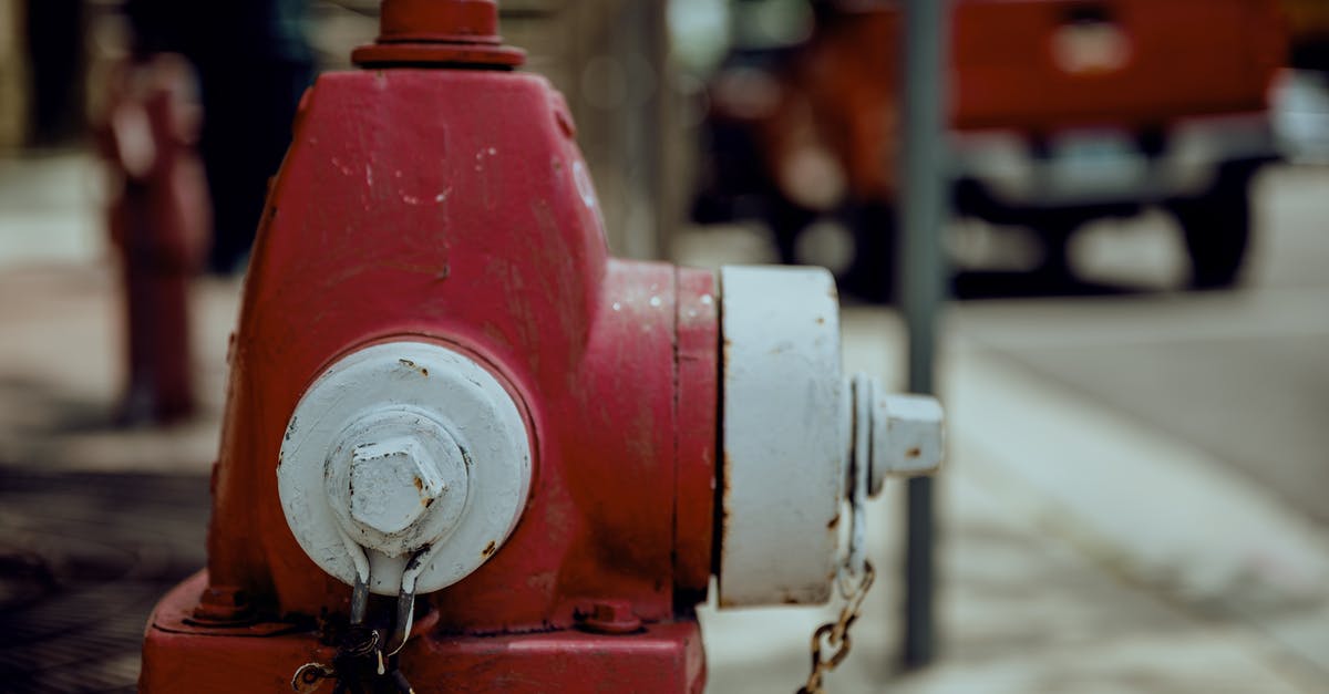 Is it safe to reheat old water in an electric kettle? - Shabby red and white metal fire hydrant with rusty chain located on city street in daytime