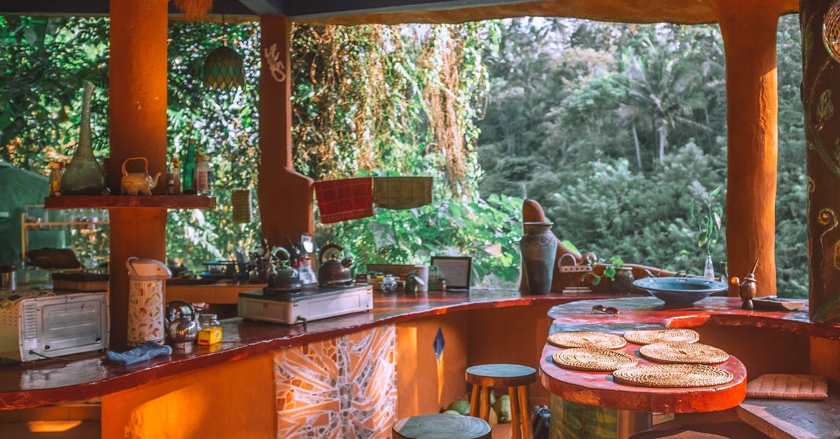 Is it safe to reheat old water in an electric kettle? - Table and stools in empty kitchen with portable stove and decorative lamps against green trees in summer