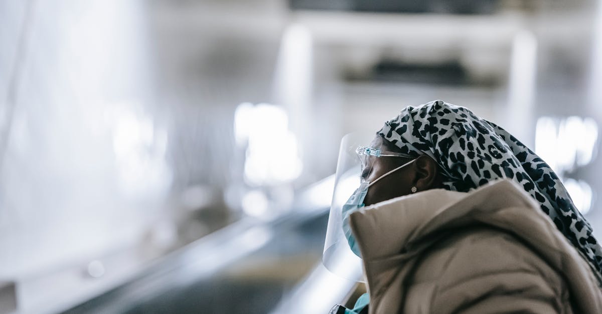 Is jerky safe concerning parasites? - Black woman in face shield and mask standing near escalator