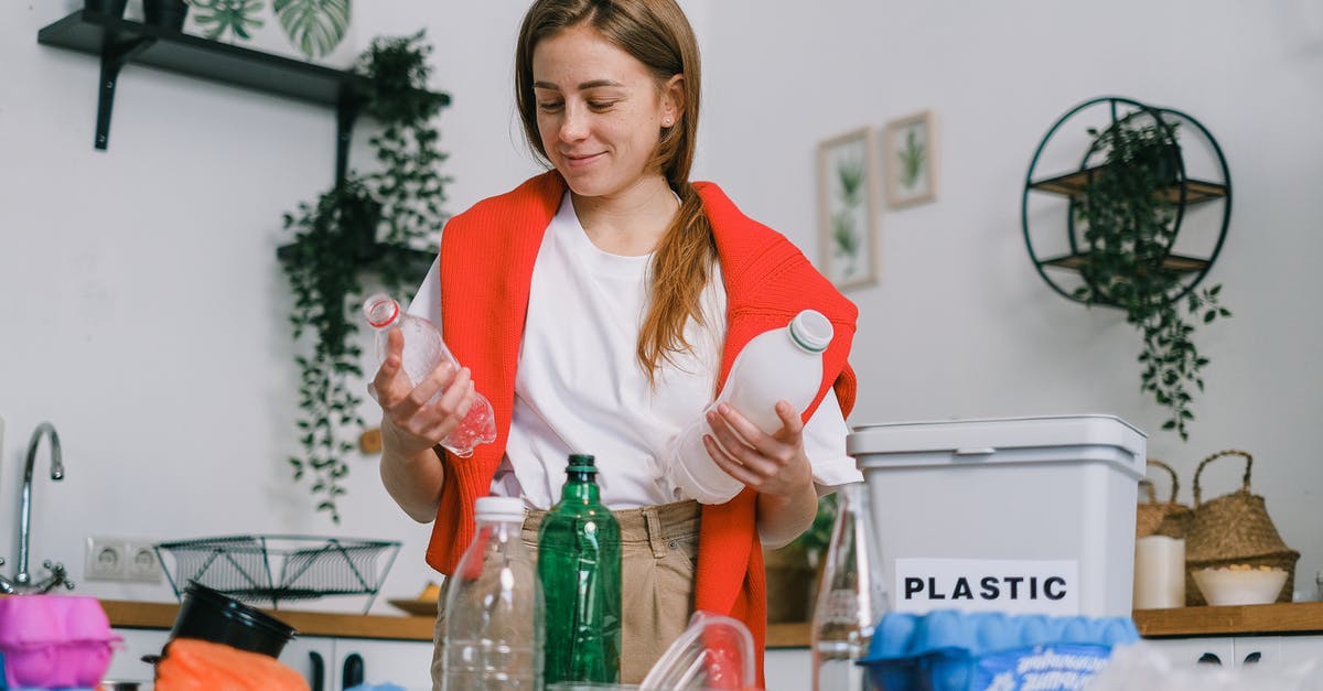 Is my pressure cooker good for the trash bin? - Cheerful female in casual clothes standing with plastic bottles in hands while sorting trash in light kitchen in daytime