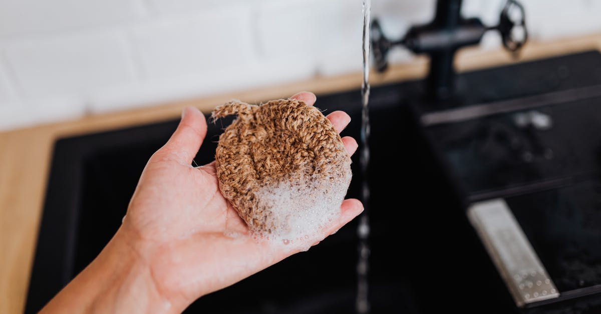 Is not using soap when washing cast iron pans safe? [duplicate] - Woman Holding an Eco Friendly Dish Sponge