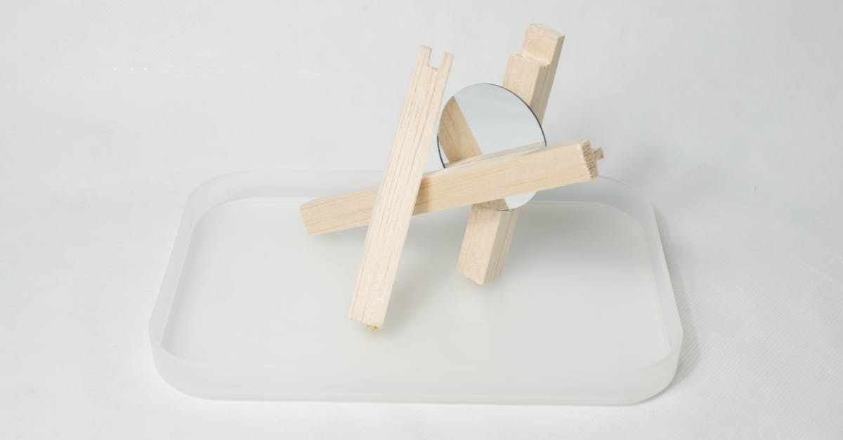 Is possible to create a transparent caramelization? - High angle of wooden sticks with mirror placed on glass stand against white background