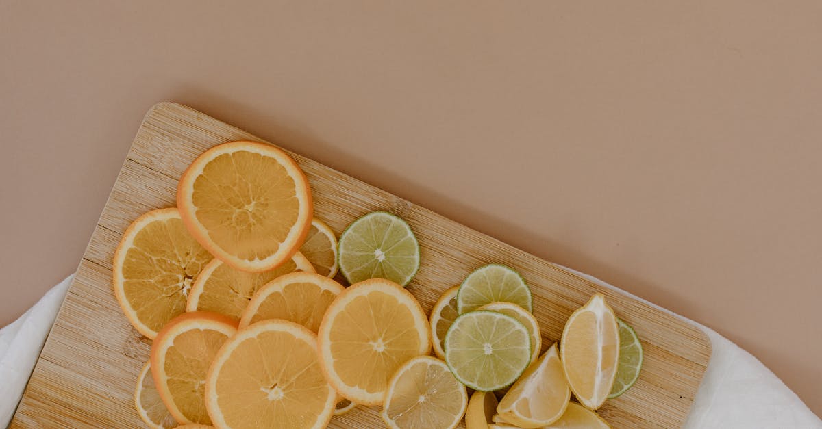 Is there a different fruit very similar to oranges? - Top view of sliced with yellow lemons near oranges and green limes on wooden cutting board on white napkin on beige surface in light place