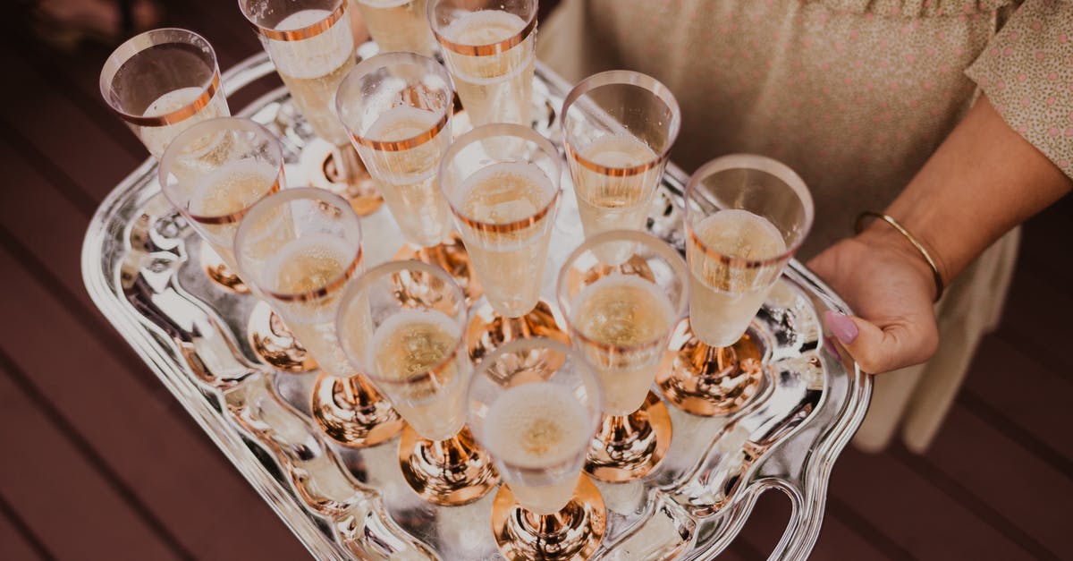 Is there a non-alcoholic beverage that has bubbles like champagne? - From above of crop female holding tray with glasses of champagne in daylight