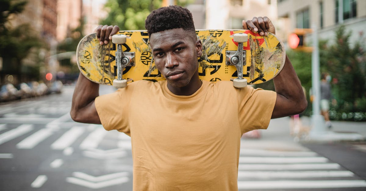 Is there a trick to scraping the beater of my stand mixer? - Serious young African American male skater with skateboard on shoulders standing on pavement near road and looking at camera