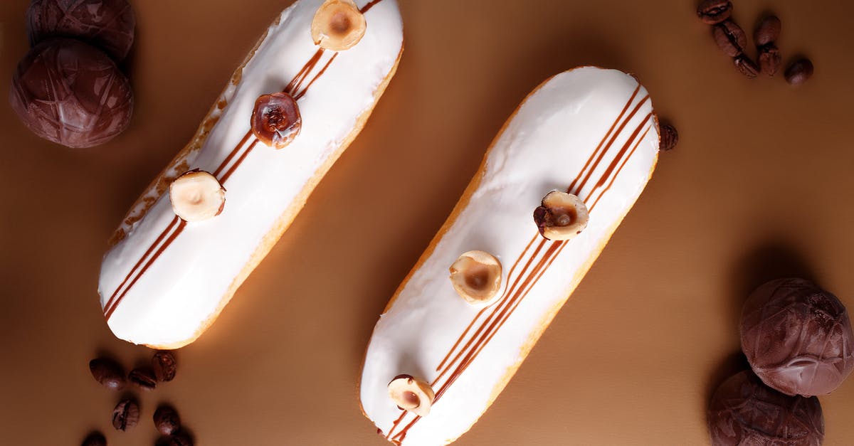 Is there a way to forestall vanilla bean marrow falling to bottom of crème? - Top view composition of sweet vanilla eclairs topped with hazelnuts and placed on brown table amidst chocolate marshmallow and coffee beans