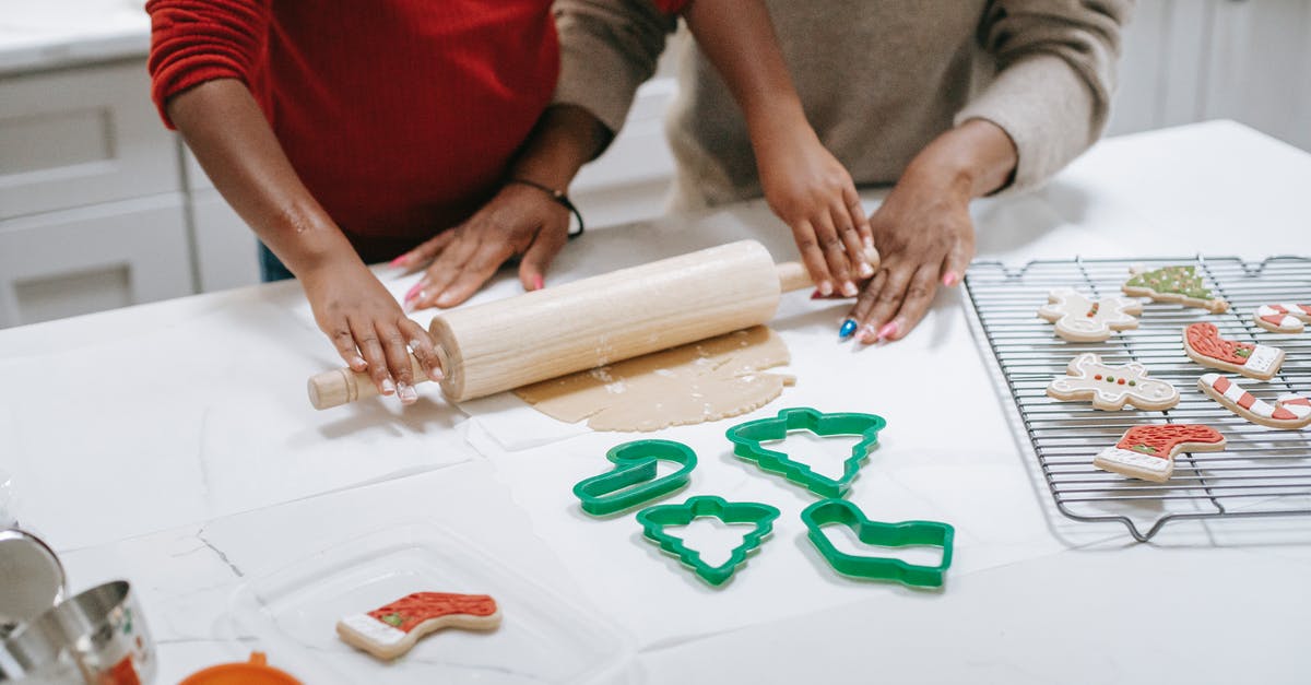Is there a way to keep chilled cookie dough from flattening while cutting it? - From above of crop unrecognizable ethnic child rolling out dough near parent while preparing gingerbread cookies in kitchen