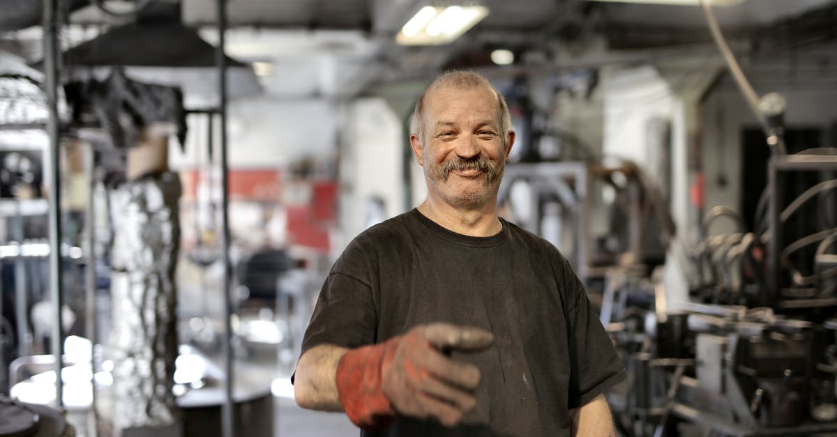 Is there an aging process by which to "oak" meat? - Cheerful senior white hair craftsman in heavy duty gloves laughing in workshop while looking at camera
