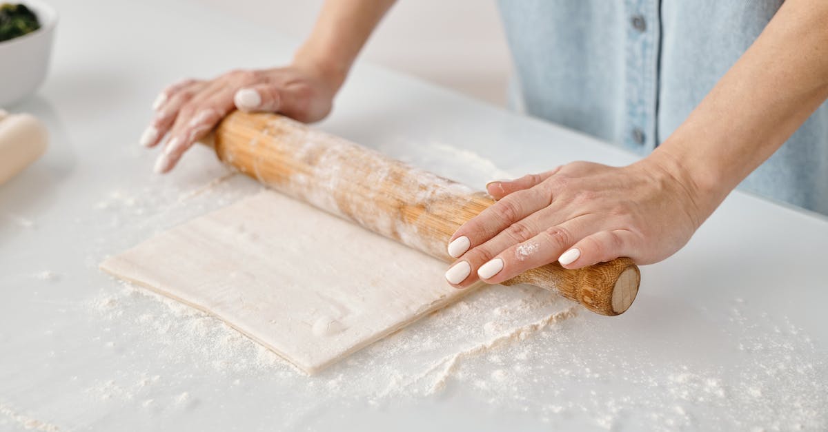 Is there an alternative to spreading flour when rolling the dough? - Crop unrecognizable chef preparing spaghetti from uncooked dough with flour using pasta rolling machine in kitchen