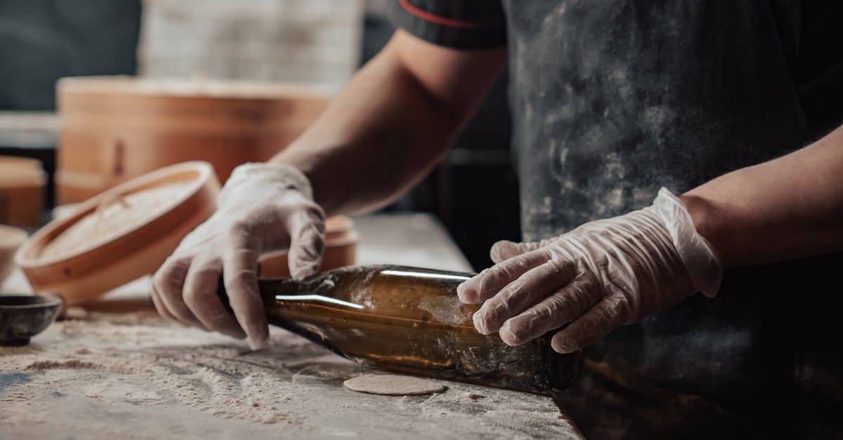 Is there an alternative to spreading flour when rolling the dough? - A Person Holding a Glass Bottle