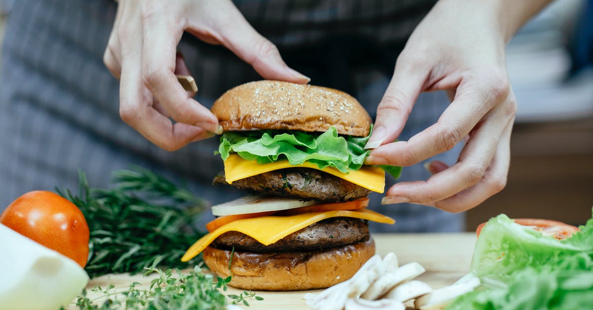 Is there an application for soft cheese rinds? - Crop anonymous female cook putting soft bread bun on top of lettuce leaves and meat patty while preparing double cheeseburger in kitchen